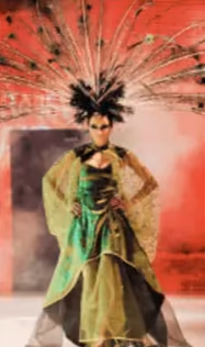 Look C: dramatic green and gold outfit with a tall feathered headpiece
